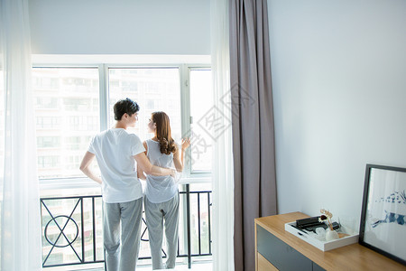 年轻情侣在窗边互动背景图片