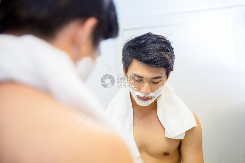 年轻男子在浴室剃须图片