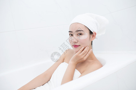 用毛巾包着包着头发坐在浴缸里敷眼膜的年轻美女背景