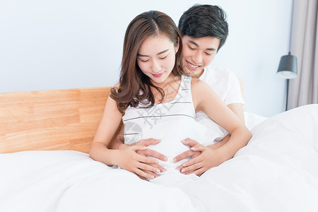 温馨孕妇夫妻一起捧着肚子期待新生儿背景