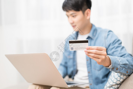 信用卡使用家居男子使用电脑手拿银行卡特写背景
