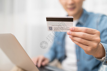 在线电脑家居男子使用电脑手拿银行卡特写背景
