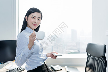 在办公室喝咖啡的自信职业女性图片