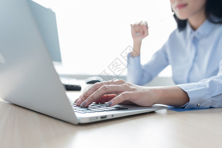 商务女性看电脑正在打字使用电脑工作手部特写背景