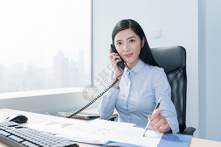 办公室里微笑打电话的职场女性图片