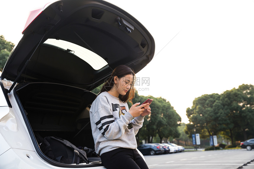 美女在后备箱低头看手机图片