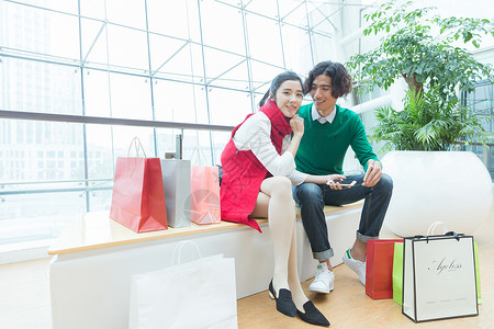 商场内年轻情侣购物休息背景图片