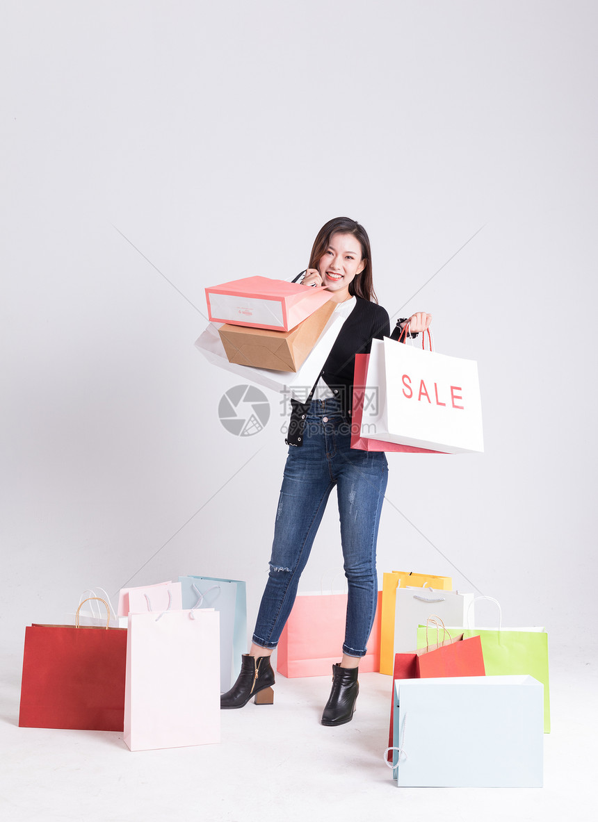 年轻女性提着购物袋看购物袋图片