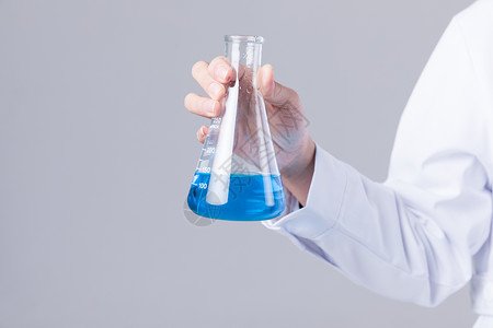 健康解决方案女科学家手拿烧杯观察蓝色液体背景
