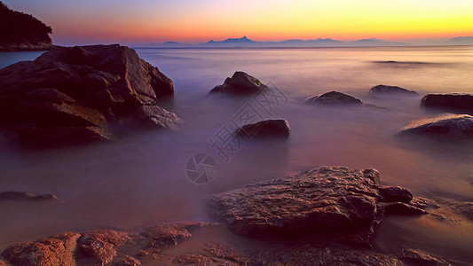 海水雾化海边乱石滩长曝夕阳风景背景