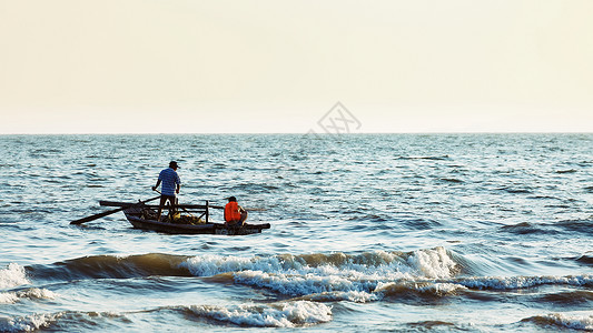 海边渔夫夕阳下海边辛勤劳动的渔民背景