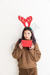 手拿礼盒带着鹿角的圣诞女性人像背景图片