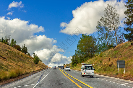 双黄线蓝天白云下交通繁忙的公路背景