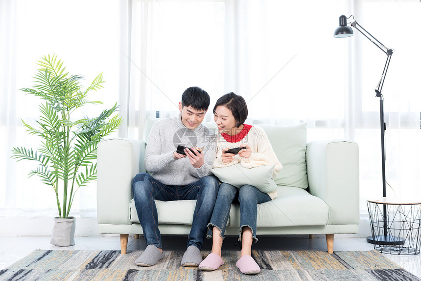 年轻情侣在客厅玩手机游戏