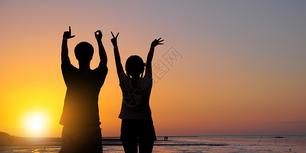 散步在海滩上的情侣情侣在夕阳晚霞下求爱设计图片