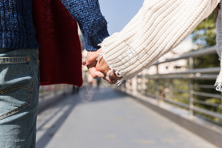 亚洲浪漫女孩年轻情侣天桥上牵手特写背景