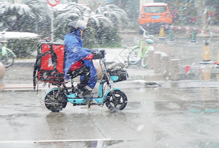 冬天穿着寒冷冬季马路骑电动车的外卖人员背景