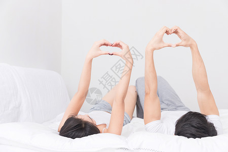 情侣枕头年轻夫妻躺床上比心背景