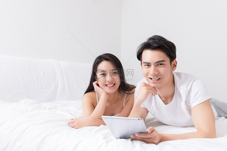 年轻夫妻床上开心看平板图片