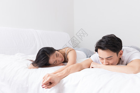年轻夫妻牵手躺床上图片