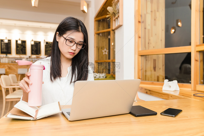 年轻女性咖啡馆内喝水图片