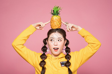 年轻双马尾女性头顶菠萝背景图片