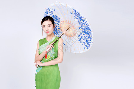 中式镂空花纹手持青花油纸伞的旗袍美女背景
