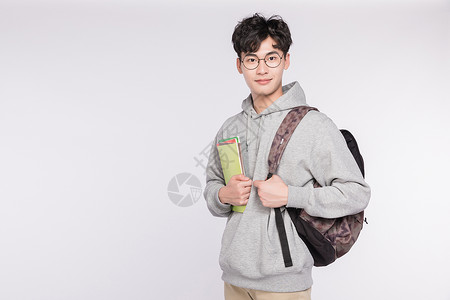 背着书包的男生背着书包抱着书准备学习的同学背景