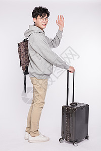 男生招手拉着行李箱打招呼的年轻人背景