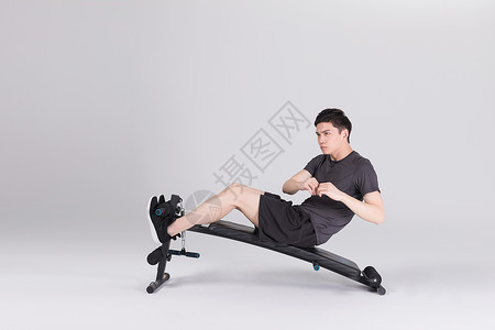 仰卧板上做仰卧起坐的健身男性背景