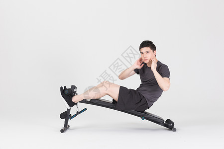 仰卧板上做仰卧起坐的健身男性背景图片