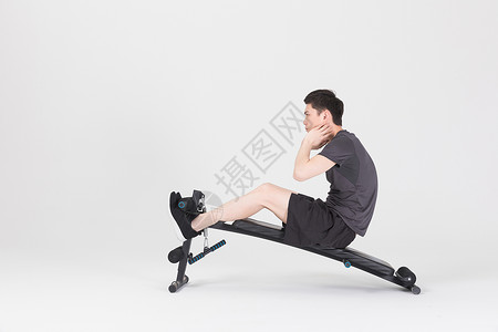 仰卧板上做仰卧起坐的健身男性高清图片