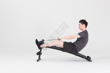 仰卧板上做仰卧起坐的健身男性坐在运动器械上拉阻力带的健身男性背景