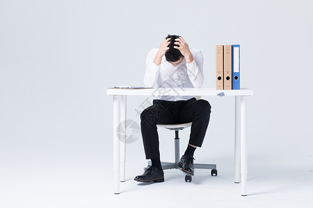 商务白衬衫坐在办公桌前低头沮丧的商务白领背景