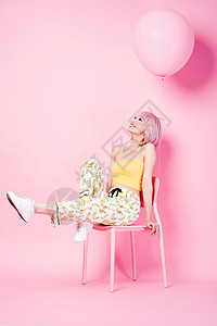 坐在粉色椅子上的俏皮时尚女模特背景图片