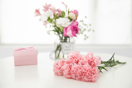 粉红色礼盒桌子上的康乃馨与礼盒背景