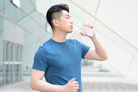 运动健身后站着喝水的年轻男性图片