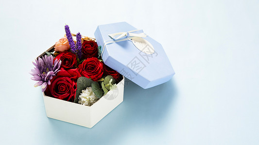 蓝色背景上装满鲜花的礼物盒背景图片