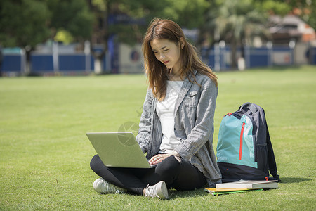 计算机学校女同学在草坪用电脑学习背景