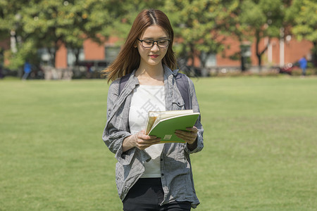 女学生在操场上走动看书高清图片素材