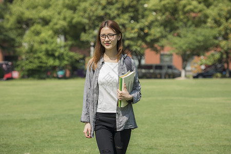 女学生在操场上走动看书高清图片素材