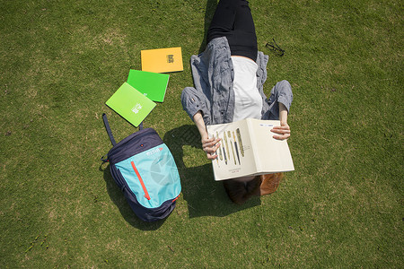 女学生躺在大学草坪上看书学习高清图片素材