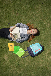 女学生躺在大学草坪上看书考试高清图片素材