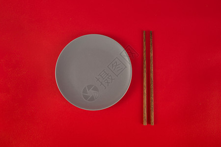 红色背景上的筷子与盘子图片