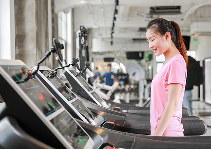 年轻女性健身房使用跑步机跑步背景
