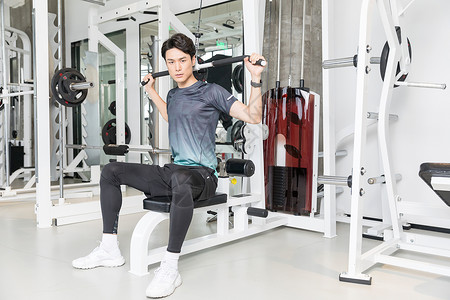 年轻男子器材健身男子健身房使用健身器械运动背景