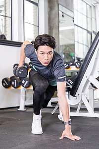 年轻男子器材健身男子健身房使用哑铃运动健身训练背景