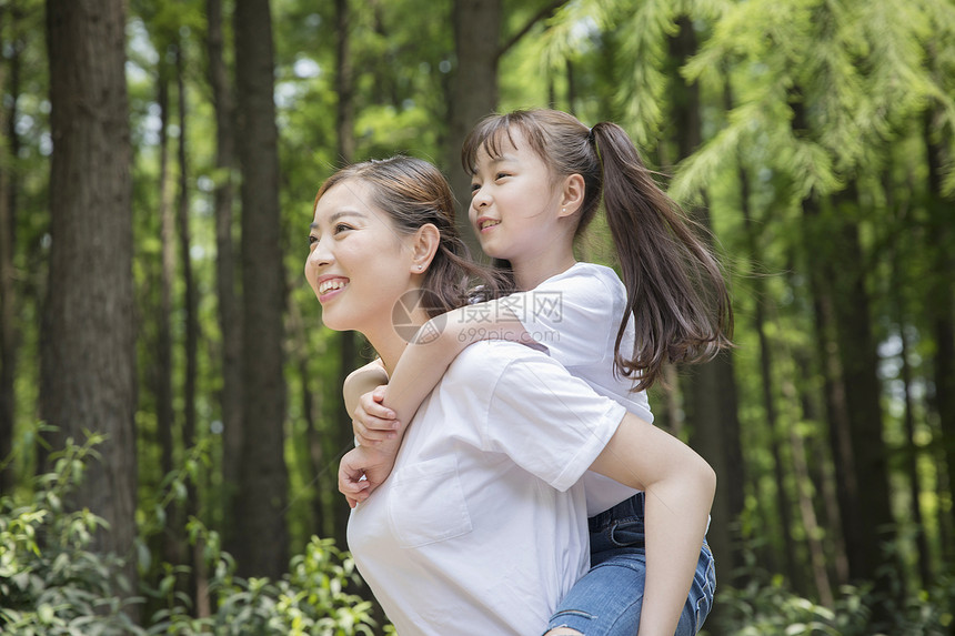 妈妈背着女儿在公园走路