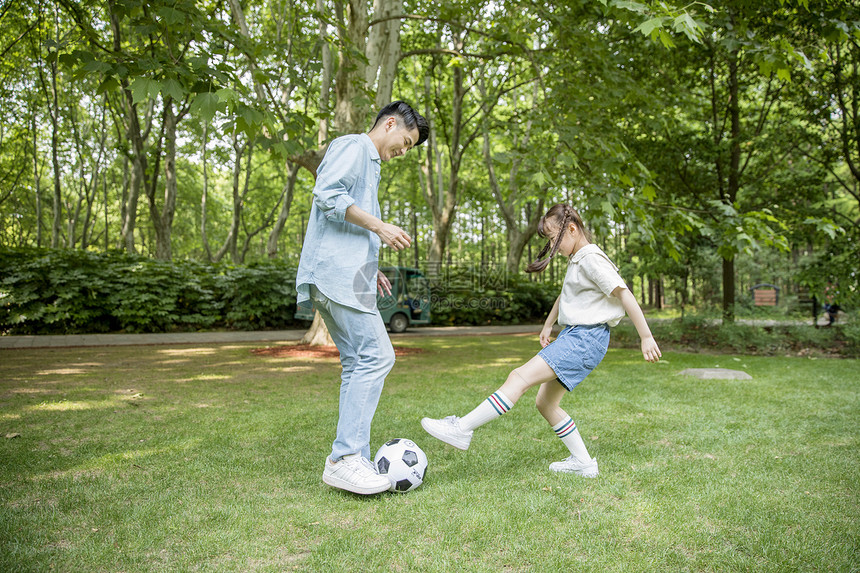 爸爸和女儿在草坪上踢足球图片