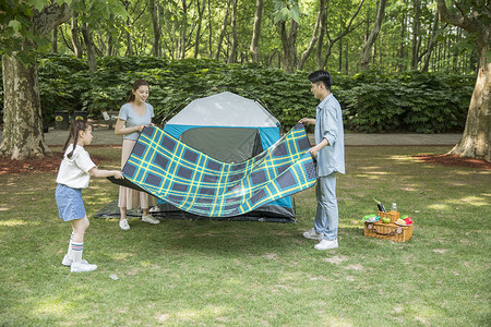 一家人郊游搭建帐篷一家人在露营时铺野餐垫背景